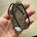 Kovový snímač k elektrické kytáře s černým kabelem. Na zadní straně je nápis „Seymour Duncan“ a „Made in USA“. V dolní části se nachází bílá nálepka…