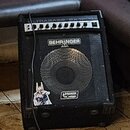 Černý basový kombo zesilovač s mřížkou před reproduktorem. Na horní hraně je nápis ULTRABASS BX1200 a pod ním ovládací panel s řadou knoflíků. Na mří…