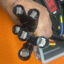 Fotografie zachycuje svazek šesti černých kabelů zakončených konektory typu RJ45. Konektory jsou průhledné s viditelnými kovovými kontakty. Na kabele…