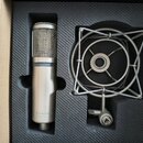 Kondenzátorový mikrofon stříbrné barvy s kovovou síťkou v horní části a šedým prstencem uprostřed. Na spodní části těla je nápis sE Electronics. Vedl…