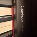 Detail digitálního piana v černé barvě s bílými a černými klávesami. Na povrchu je viditelný nápis Clavinova a model CLP-440. Vedle USB portu je text…