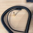 Černý spirálový kabel s pozlacenými konektory. Na fotce je vidět jedna strana kabelu s konektorem a samostatný pozlacený adaptér. Na kabelu nejsou žá…