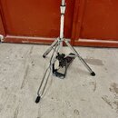 Stříbrný kovový stativ s rozkládacími nohami a černými gumovými koncovkami. V horní části je vidět teleskopický mechanismus s utahovacím prvkem. Povr…