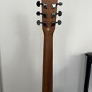Zadní strana hředu a hlavy akustické kytary z hnědého dřeva. Na zadní straně hlavy je nápis „Taylor Guitar Company“ a pod ním menší text „UNITED STAT…