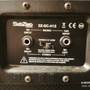 Detail zadní strany kytarového cabinetu s černým plastovým panelem. Je na něm uveden název SubZero GUITARS a model SZ-GC-412 spolu s certifikačními s…