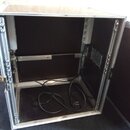 Otevřený transportní kufr s hliníkovými hranami a černým vnitřním povrchem. Uvnitř jsou vidět černé elektrické kabely a na pravé stěně je umístěn kov…