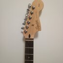 Fotografie zachycuje hlavu a hриф kytary z přírodního světlého dřeva s tmavým hmatníkem. Na hlavě je vidět nápis Squier, JAZZMASTER® a Affinity Serie…