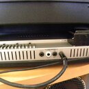 Detail zadní strany stříbrného rackového zařízení s ventilací ve formě svislých rýh. Jsou zde viditelné konektory s nápisy INSERT, CHANNEL a FOOTSWIT…