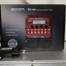 Červený basový efektový procesor Zoom B1 FOUR v originální krabici. Na zařízení jsou viditelné nápisy „B1 FOUR“, „ZOOM“ a „Multi-Effects Processor“.…