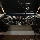Fotografie zachycuje otevřený černý transportní case, ve kterém je umístěno rackové zařízení s řadou zapojených kabelů. Viditelný je rozsáhlý systém…