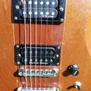 Detail těla elektrické kytary v dřevěném provedení se dvěma humbuckery. Horní snímač má nápis R.M. pickups, spodní snímač nápis Seymour Duncan. Kytar…