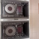 Dvě černé CDJ jednotky značky Pioneer umístěné v transportním kufru s hliníkovým profilem. Na obou zařizeních je viditelné logo Pioneer a nápis CDJ-1…