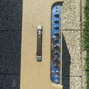 Kytarový zesilovač v béžovém textilovém potahu s hnědým koženým úchem. Modrý ovládací panel obsahuje nápisy INPUTS, NORMAL, VOLUME, PRE, POST, REVERB…