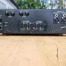 Zadní strana černého zesilovače s několika konektory a přepínači. Jsou zde nápisy MAINS FUSE 5 A, POWER 220 V, FUSE CHANNEL B 3,15 A a FUSE CHANNEL A…