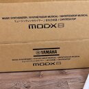Kartonová krabice s nápisy v několika jazycích. Je na ní viditelné logo YAMAHA a model MODX8. Text uvádí MUSIC SYNTHESIZER / SYNTHÉTISEUR MUSICAL / S…