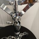 Detail chromovaného kovového stojanu s rozkládacím mechanismem. Na středové části je viditelný nápis MAN®. Povrch je lesklý, v horní části jsou vidit…
