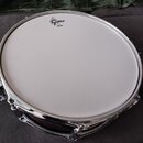 Bílá bubenová blána s černým logem Gretsch a menším nápisem pod ním, který je nečitelný. Buben má chromovaný obruč a kovové úchytky. Tělo bubnu je v…