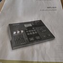 Fotografie zachycuje stránku uživatelské příručky s obrázkem elektronického bubnového modulu. Na papíře je uveden text Millenium, MPS-850 e-drum modu…