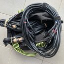 Svršek černé kabelové tašky s neonově žlutými popruhy, ve které jsou svinuté černé audio kabely. Kabely mají konektory typu XLR a jack, přičemž někte…