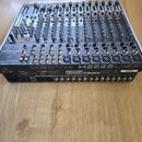 Stříbrný mixážní pult s černými ovládacími prvky. Na přední straně je uveden název modelu XENYX X2222USB a logo behringer. Na zadní straně je viditel…