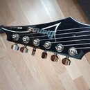 Černá hlava elektrické kytary s chromovanými ladičkami. Na povrchu je bílý nápis Ibanez a text RG SERIES. Povrch je lesklý, bez viditelných poškození.