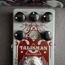 Kytarový efekt pedál v šedém provedení s červeným grafickým potiskem. Na spodní části je nápis catalinbread MECHANISMS OF MUSIC a uprostřed výrazný t…