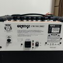 Zadní strana kytarového komba značky ORANGE, model CRUSH 20RT. Na bílém štítku jsou uvedeny technické specifikace, včetně výkonu 20 WATTS RMS a sério…
