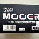 Černá krabice s bílými a červenými nápisy. Na povrchu je uveden název GROOVE LOOP X2, značka MOOER a označení X2 SERIES. V pravé dolní části jsou úda…