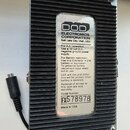 Zadní strana efektového pedálu s černým žebrovaným kovovým šasi. Na středu je bílá nálepka s nápisem DOD ELECTRONICS CORPORATION Salt Lake City, Utah…