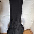 Černý polštovaný pouzdro (gigbag) na hudební nástroj. Má dvě nastavitelné ramenní popruhy s plastovými spřážkami a rukojeti. Povrch je v dobrém stavu…