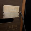 Detail zadní strany hnědého hudebního nástroje s dřevěnou strukturou. Na přístroji jsou dvě bílé štítky a nápis přímo na povrchu: FARFISA mod. 4290-R…