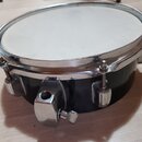 Černý buben s bílým blánou a chromovaným obručem. Na korpusu jsou viditelné chromované lugy a mechanismus pro napnutí blány. Nástroj nevykazuje výraz…
