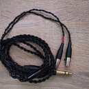 Černý pletený kabel s jedním 6,3mm jack konektorem a dvěma XLR konektory. Kabel je v dobrém stavu, jeden z XLR konektorů má červený značkový prstenec…
