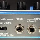 Zadní strana modrého efektového pedálu značky BOSS. Jsou zde vidět vstupy a výstupy s nápisy INPUT R (MONO) L, OUTPUT R (MONO) L a PHONES, přepínač G…