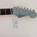 Modrá elektrická kytara s hnědým hmatníkem. Na hlavě je zlatý nápis Squier BY FENDER a STRATOCASTER®. K nástroji je přivázána bílá kontrolní karta s…