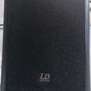 Černý reproduktor s texturovaným povrchem. Ve spodní části je umístěno logo LD SYSTEMS. Nástroj stojí na bílém stole.