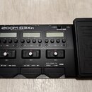 Černý kytarový efektový procesor s nápisem ZOOM G3Xn Multi-Effects Processor. Zařízení má tři LCD displeje, několik ovládacích knoflíků a tři spodní…