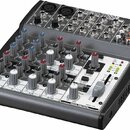 Míchací pult značky BEHRINGER, model XENYX 1002. Zařízení má šedý povrch s černými detaily, obsahuje řadu potenciometrů, posuvníků a vstupních konekt…