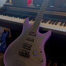 Fialová elektrická kytara s matným povrchem a černým hmatníkem. Na těle jsou vidět tři humbuckery, ovládací knoflíky a mřížka reproduktoru v dolní čá…