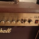 Detail kontrolního panelu hnědého kytarového komba s kovovým předním panelem. Na panelu jsou nápisy Acoustic AS50D Soloist a značka Marshall na spodn…