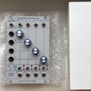 Modul syntezátoru v bílém provedení s nápisem QUAD LOPASS GATE MODEL 2921 a BUCHLA & TIPTOP AUDIO. Modul obsahuje čtyři modré otočné knoflíky, několi…