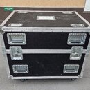 Černý transportní case s kovovými hranami a rohy. Má dvě řady úchytů a dva kovové zámky v uprostřed. Povrch vykazuje drobné škrábance a známky použív…