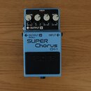 Modrý efekt pedál s černým spínacím tlačítkem. Na přední straně je bílý nápis SUPER Chorus CH-1 a v dolní části logo BOSS. Horní panel obsahuje čtyři…