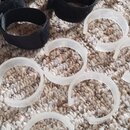 Na fotografii je skupina kabelových stahovacích pásků rozložených na koberci. Horní část tvoří šest černých textilních pásků s velcro zapínáním. Spod…