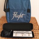 Modrá látková taška s bílým nápisem Flight. Vedle ní je černý pouzdro, ve kterém se nachází bílý efektový pedál s nápisy DAPPER a model DELAY, CHORUS…