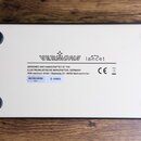 Spodní strana bílého obdélníkového zařízení s четыma černými gumovými nožičkami v rozích. Uprostřed je černý nápis VERMONA lancet a text DESIGNED AND…