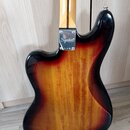 Zadní strana elektrické basy s tělem v provedení sunburst. Na kovové spojovací desce mezi krkem a tělem je bílý nápis Squier® a pod ním symboly CE a…