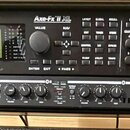Černý rack s dvěma zařízeními. Horní jednotka má nápisy FRACTAL AUDIO SYSTEMS a Axe-Fx II XL, dále označení PREAMP/EFFECTS PROCESSOR, displej a řadu…