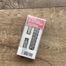Krabice s kytarovým mostem a tailpiece v chromovaném provedení. Na červeném štítku je nápis GOTOH Electric Guitar Guitar Bridge Tail Piece. Dole na o…