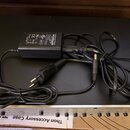 Černý síťový adaptér s nápisem FRYETTE AC ADAPTER. Na štítku jsou viditelné certifikace CE, RoHS a nápis MADE IN CHINA. Adaptér je připojen k černému…